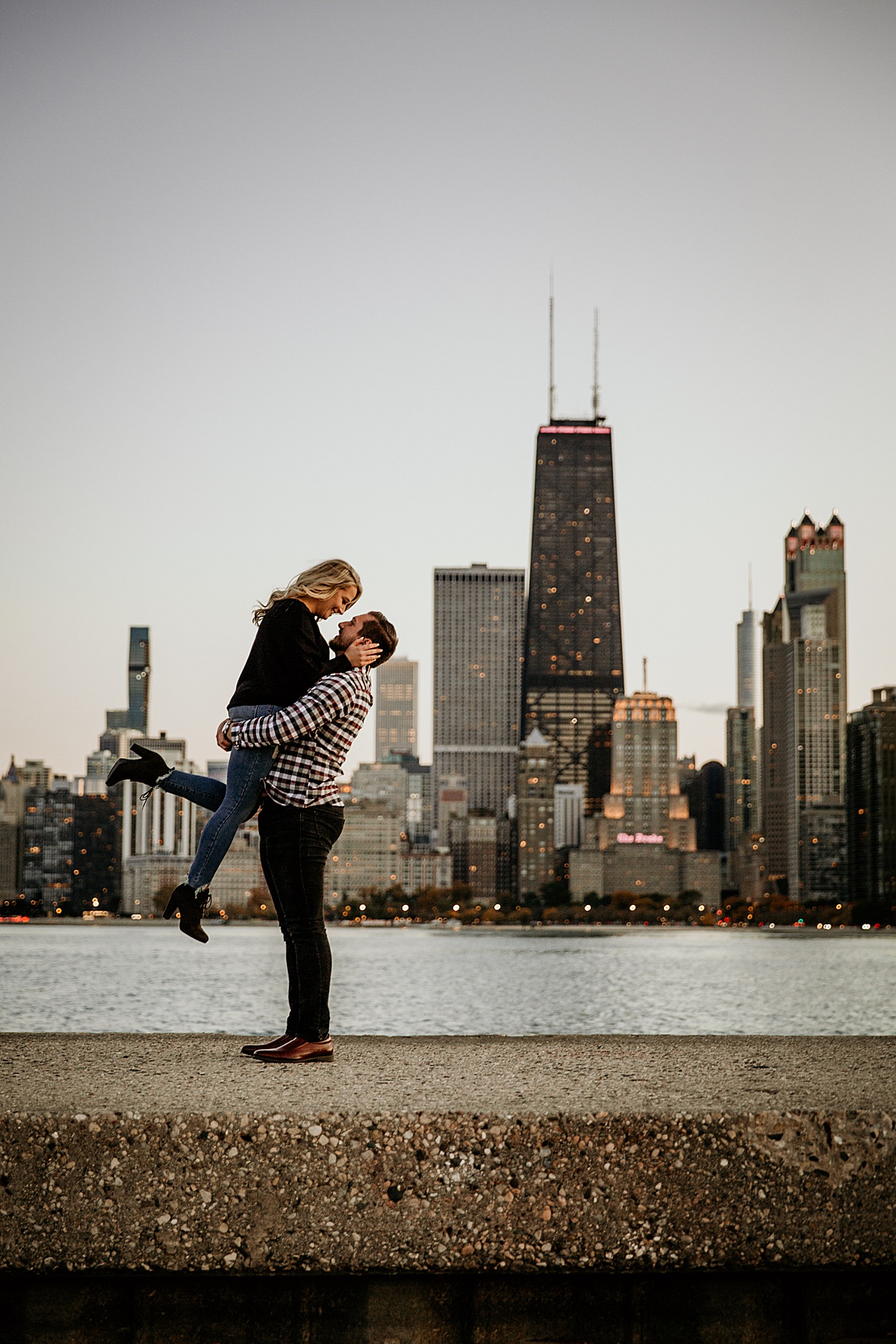 Guy lifting a girl up romantically with the chicago skyline in the background
