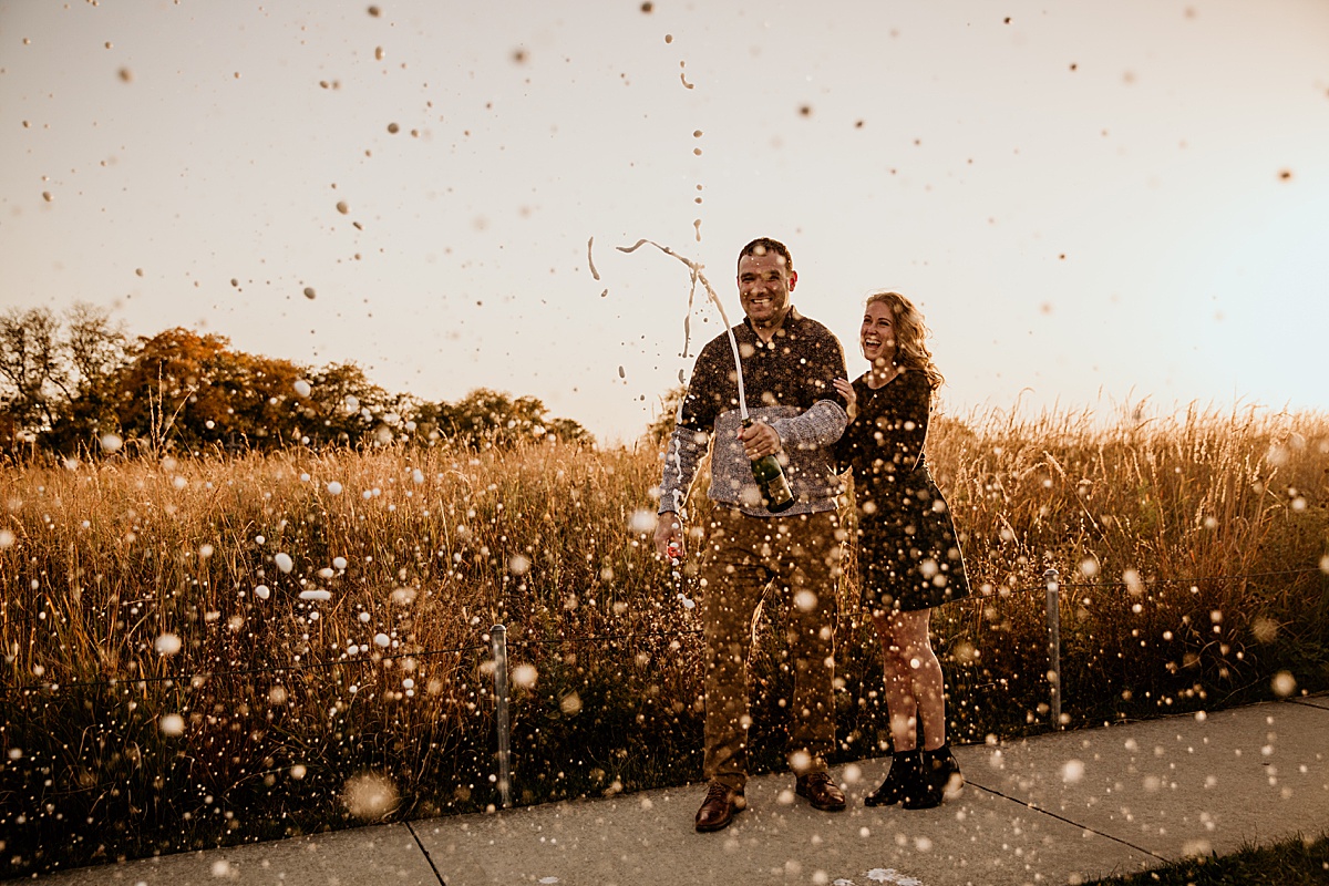 Couple popping champagne at sunset.