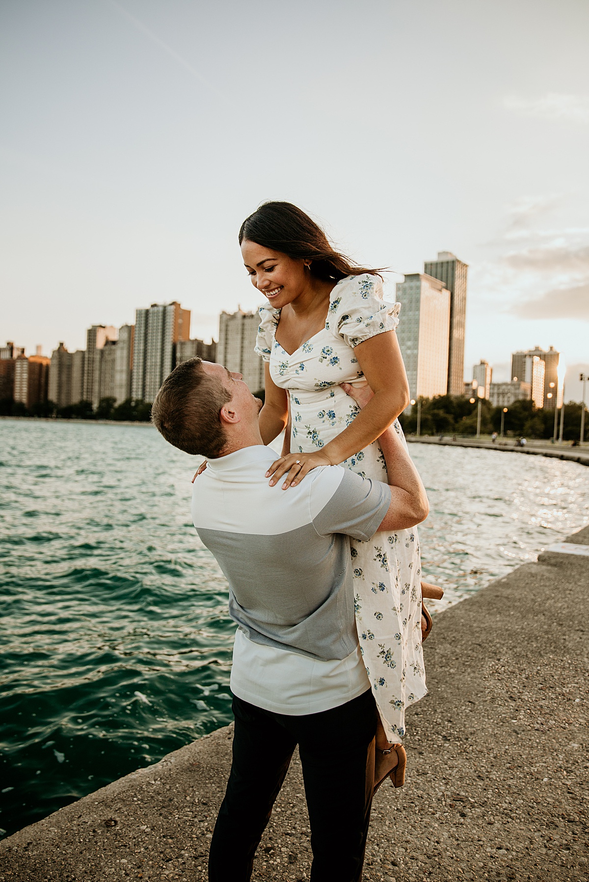 Guy lifting up a girl by Lake Michigan with the Chicago Skyline behind them.
